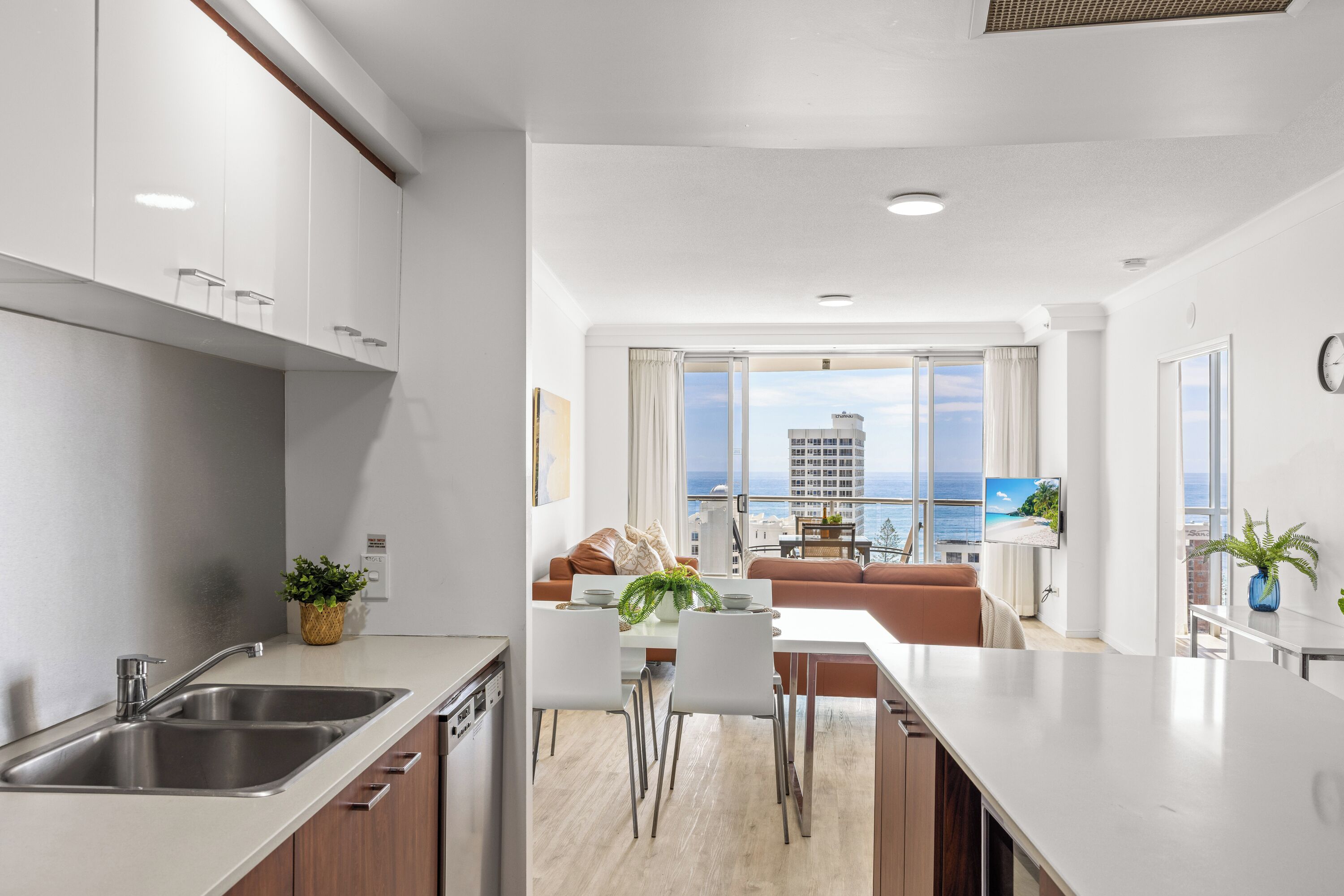 Une cuisine moderne avec un coin repas, de grandes fenêtres et une vue sur la ville et l’océan.