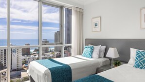 Een hotelkamer met twee bedden, een groot raam met uitzicht over de stad en een balkon.