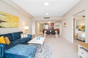 A modern hotel room with a sofa, a dining table, and a kitchen area. - Chevron Renaissance Garden View (Surfers Paradise)