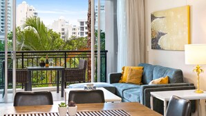 A modern living room with a balcony, a sofa, a dining table, and a painting on the wall. - Chevron Renaissance Garden View (Surfers Paradise)