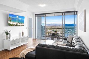 Relax in this stylish living room with a large flat-screen TV, comfortable sofa, and city views from the balcony.