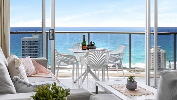 A balcony with a view of the ocean, a table with chairs, and a sofa. - Chevron Renaissance Ocean View (Surfers Paradise)