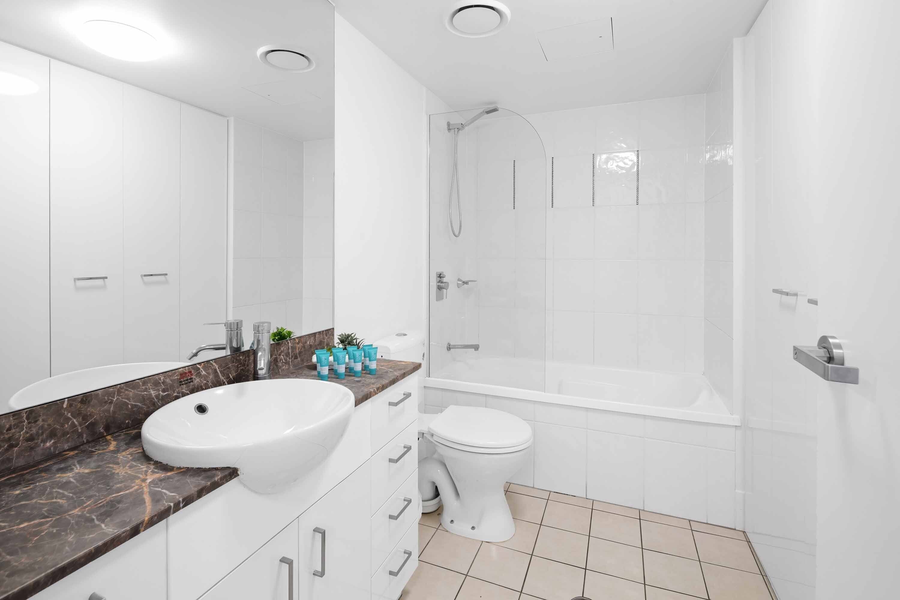 A modern bathroom with a white sink, toilet, and shower.