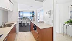 Una cocina moderna con una isla central, muebles blancos y vistas al mar a través de amplios ventanales.