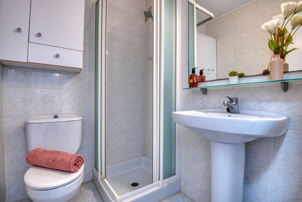Une salle de bain avec des toilettes, une douche et un lavabo.