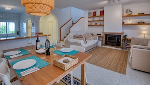 Ein modernes Wohnzimmer mit Essbereich, Holzmöbeln, Kamin und Treppe.