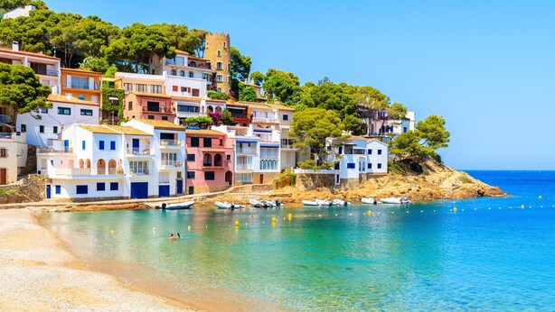 Una cittadina costiera con edifici colorati, acque blu cristalline e barche sulla riva.