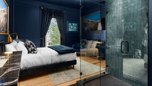 Une chambre à coucher moderne avec un lit, une table de chevet et une cabine de douche en verre.
