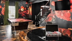Une salle de billard équipée d’une table de billard, de billes et d’une table de poker avec des jetons.