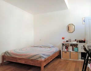 A bedroom with a wooden bed, a white wall, a mirror, and a bookshelf. - Appartement a Endoume (Marseille)