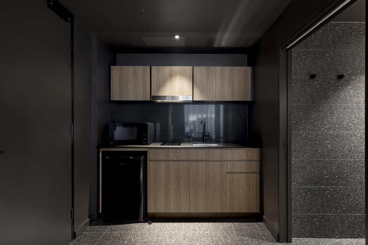 A compact kitchen with wooden cabinets, a microwave, and a dishwasher.