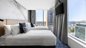 Habitación de hotel con dos camas, un ventanal grande con vista a la ciudad y un diseño moderno.