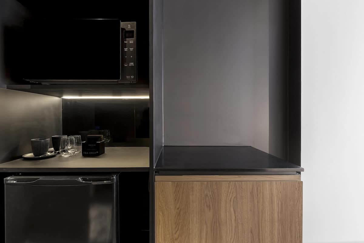 A modern kitchen with a microwave, a coffee maker, and a small refrigerator.