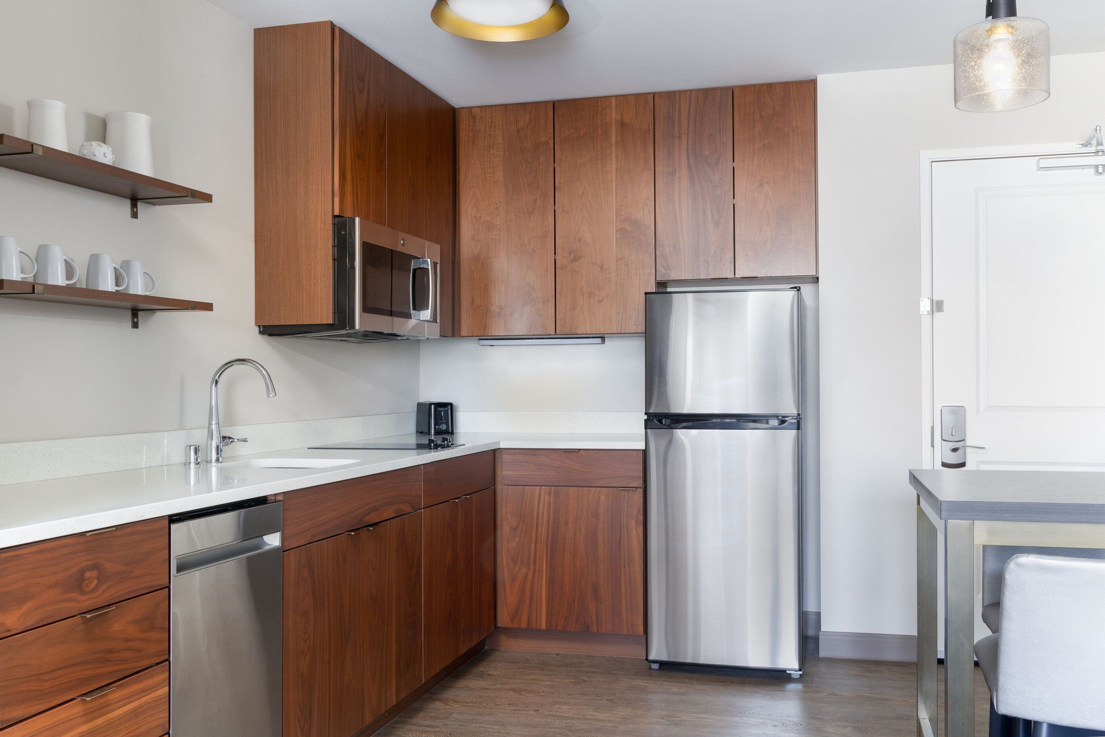 Une cuisine moderne avec des meubles en bois, des appareils en acier inoxydable et un plan de travail blanc.
