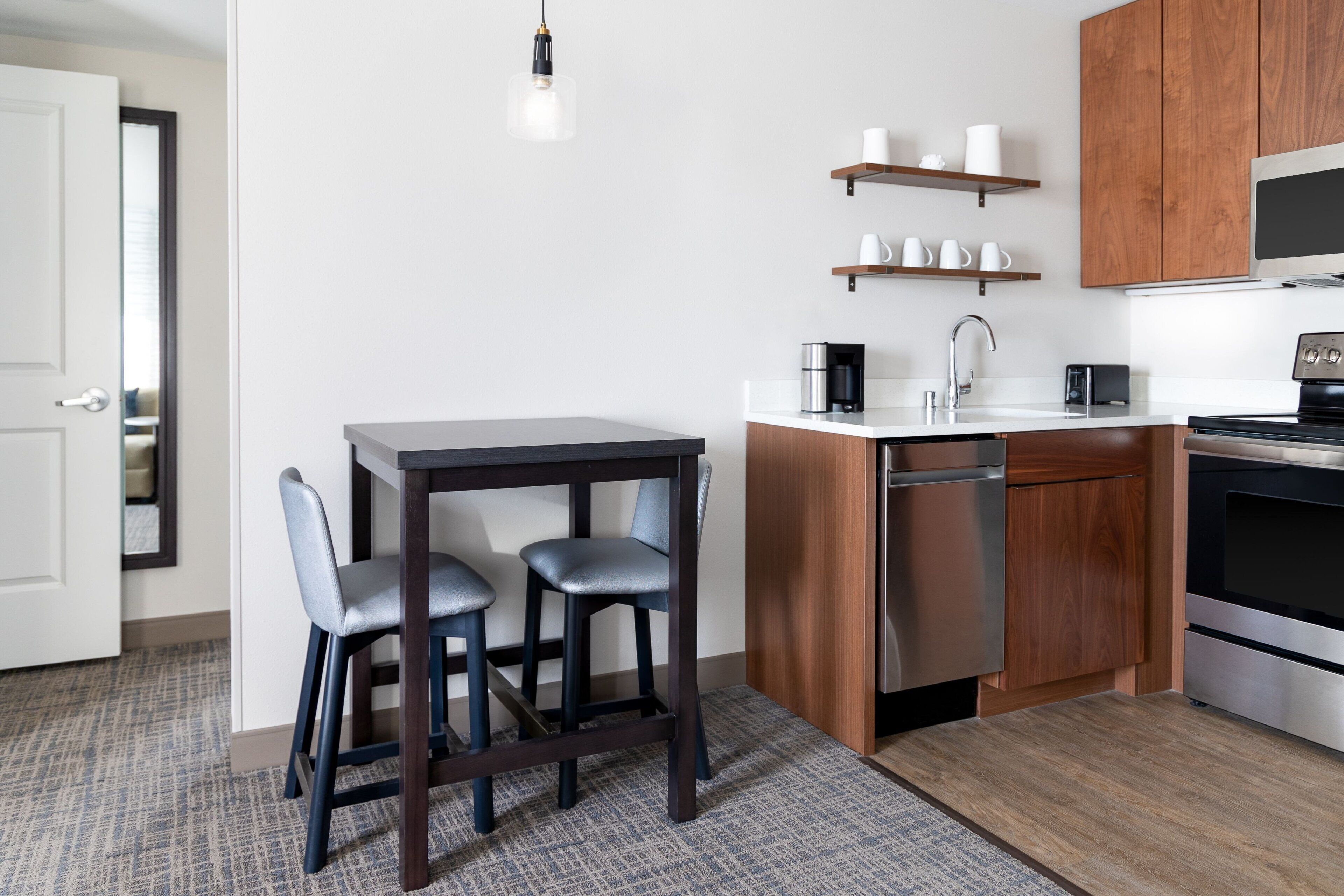 Una cocina moderna con una mesa y sillas de madera oscura, electrodomésticos de acero inoxidable y armarios de madera.