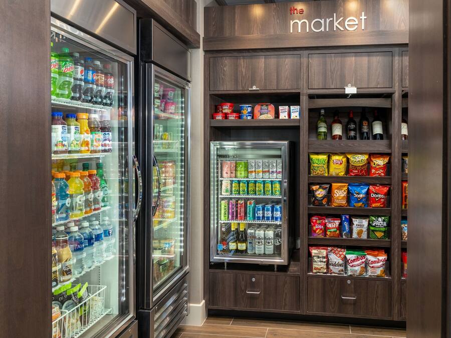 A refrigerated beverage and snack display in a market area with various drinks and snacks.
