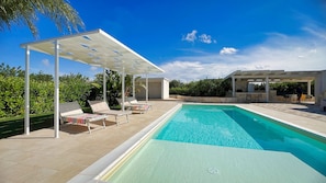 Une piscine avec des chaises longues et un espace de détente abrité.