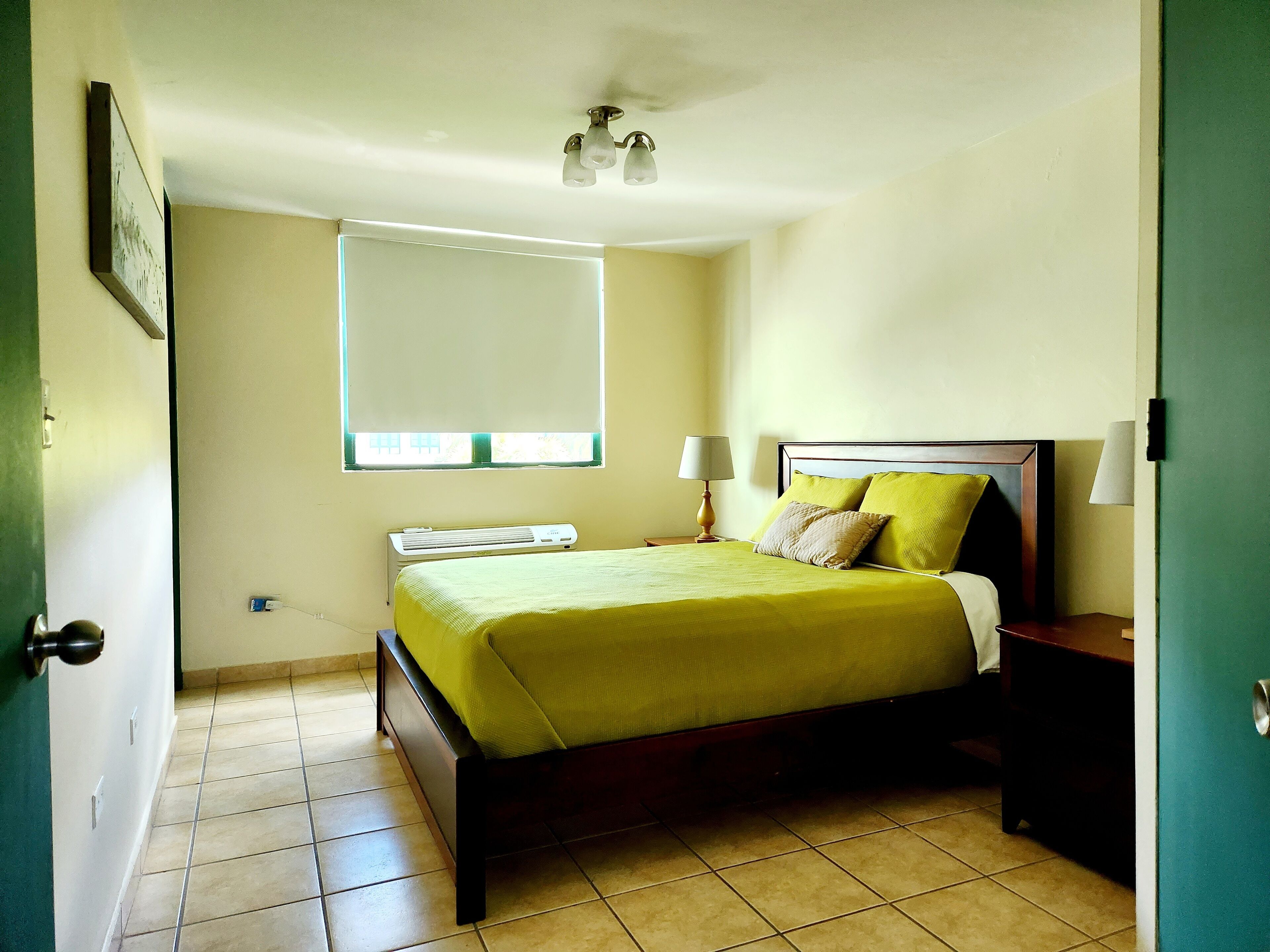 Una camera da letto con un letto, un comodino, una lampada e una finestra con persiane.