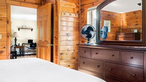Una stanza con rivestimento in legno, un letto, una cassettiera, uno specchio e una ventola.
