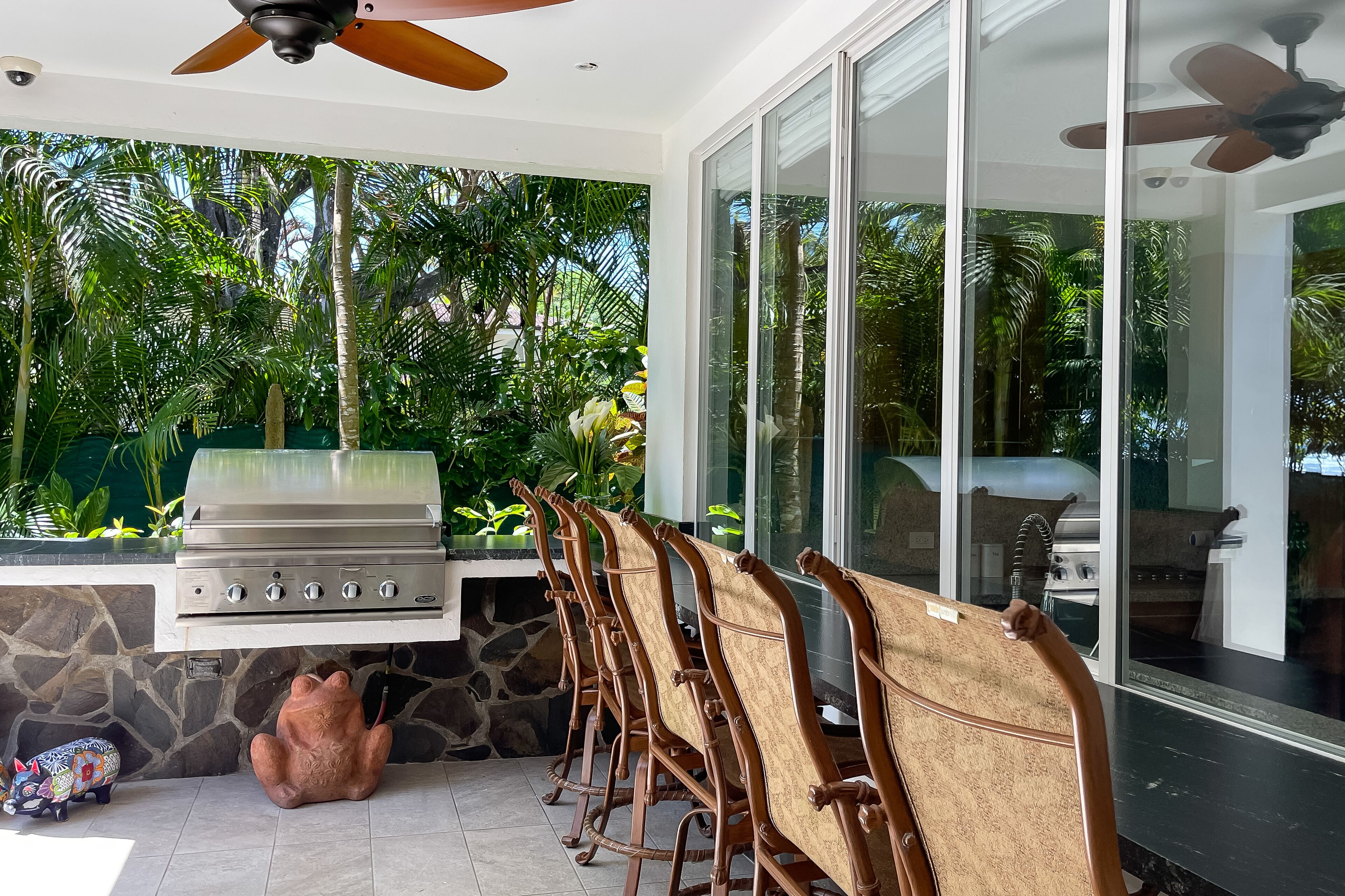 An outdoor kitchen area with a grill, stone wall, and chairs.