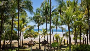 Vista da praia com palmeiras e céu claro.