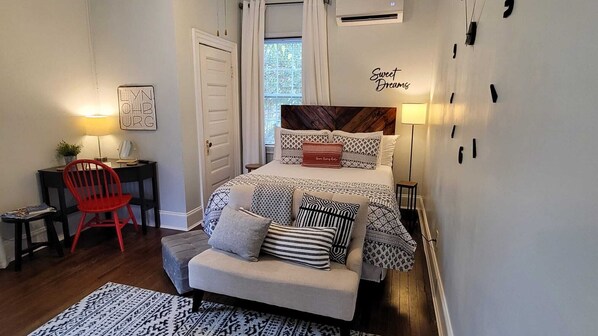 A bedroom with a bed, bedside table, chair, and a wall with a sign.