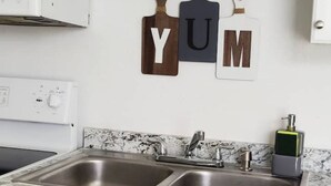 Una cocina con dos fregaderos, una estufa blanca y un dispensador de jabón en la pared.
