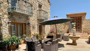 An outdoor patio with wicker furniture, stone walls, and a fountain. - Spacious apartment in Historical Country Estate (Teulada)