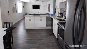 A modern kitchen with white cabinets, a central island, a built-in oven, and a large refrigerator. - Convenient, cozy and bright  :)  (New Port Richey)