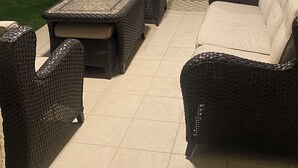 An outdoor patio with wicker furniture, a table, and chairs.