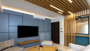 Una sala de estar moderna con un televisor de pantalla plana, una mesa de centro de madera y un sofá.