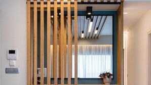 Una habitación con un separador de madera, una pared azul e iluminación lineal en el techo.