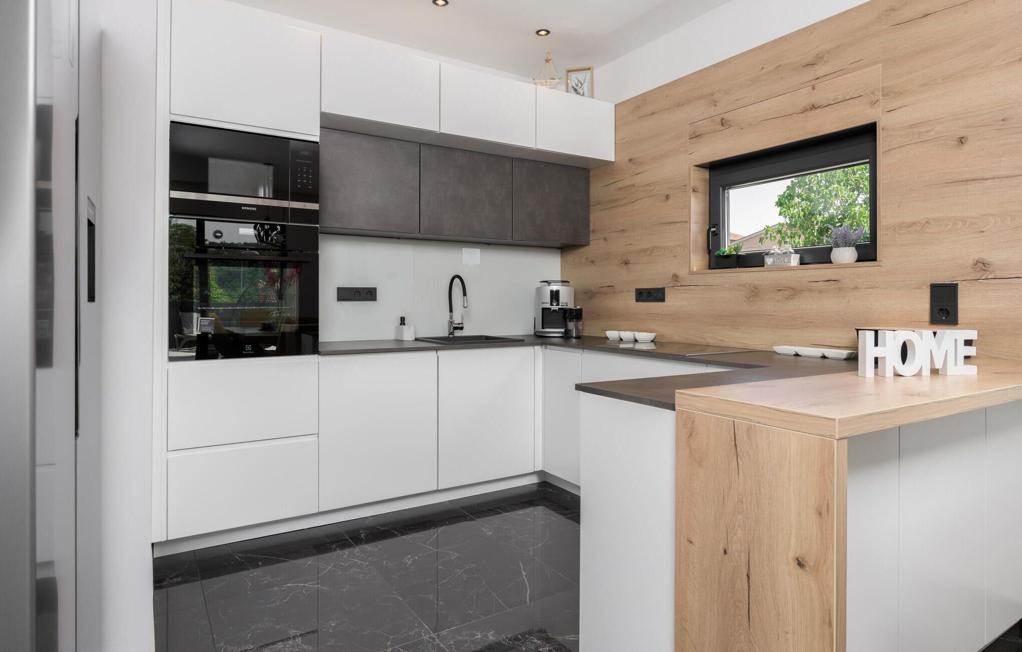 A modern kitchen with white cabinetry, a built-in oven, and a coffee maker.
