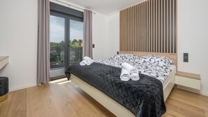 Een moderne slaapkamer met een groot bed, een houten hoofdbord en een balkon met gordijnen.