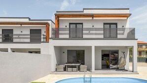 Een modern herenhuis met zwembad, terras en balkon.