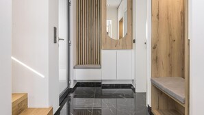 Een moderne hal met een wand van houten panelen, een spiegel en een bankje.