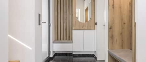 A modern hallway with a wooden panel wall, a mirror, and a bench.
