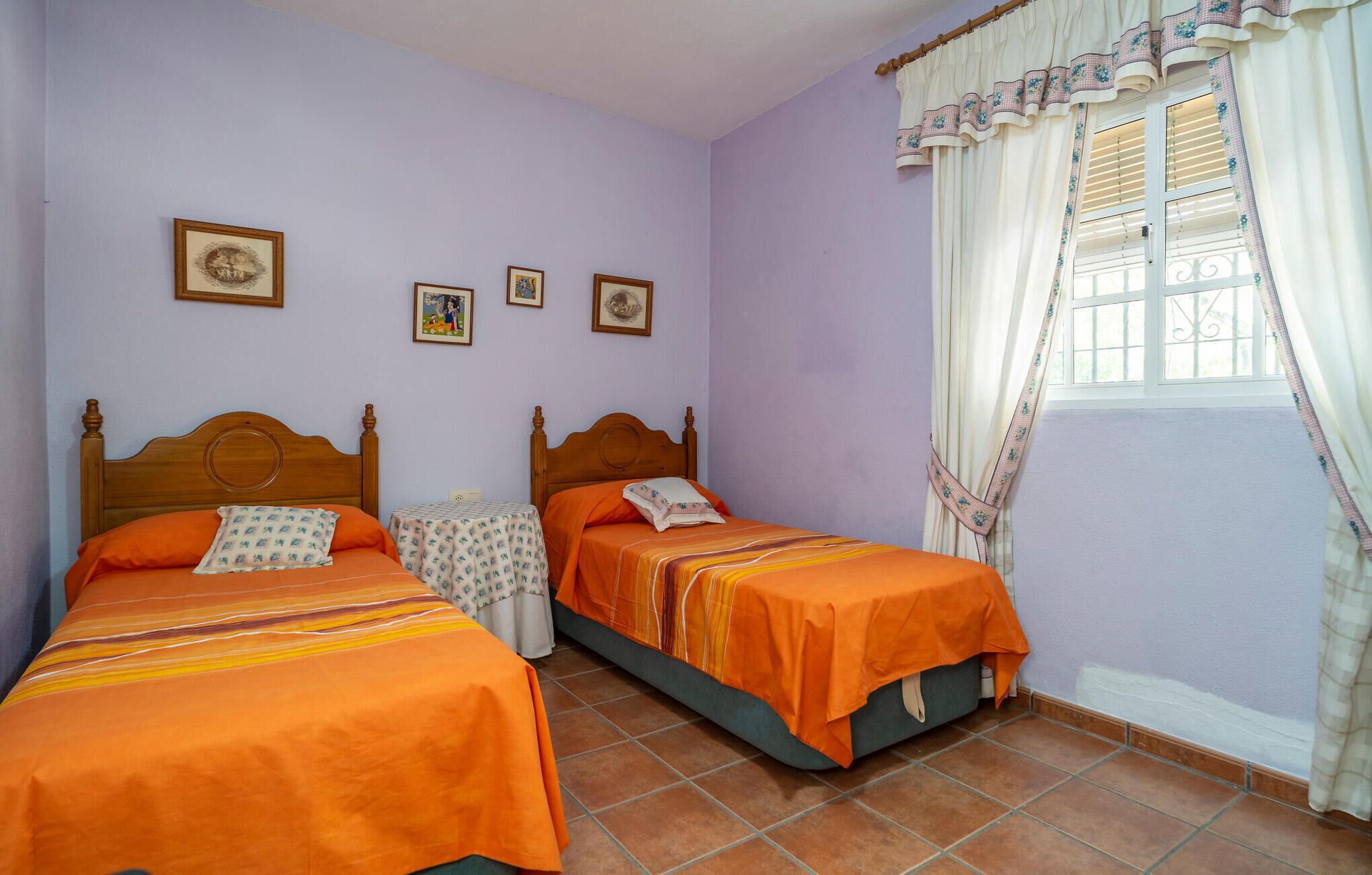 Un dormitorio con dos camas individuales, una mesita pequeña y una ventana con cortinas.