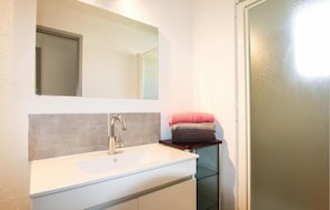 A bathroom with a white sink, a mirror, and a towel rack with folded towels.