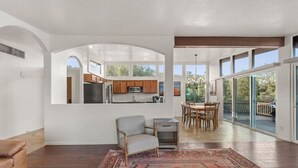 A spacious living area with a kitchen, dining table, and a large rug. - Walk to Uptown with Breathtaking Views and HotTub! (Sedona)