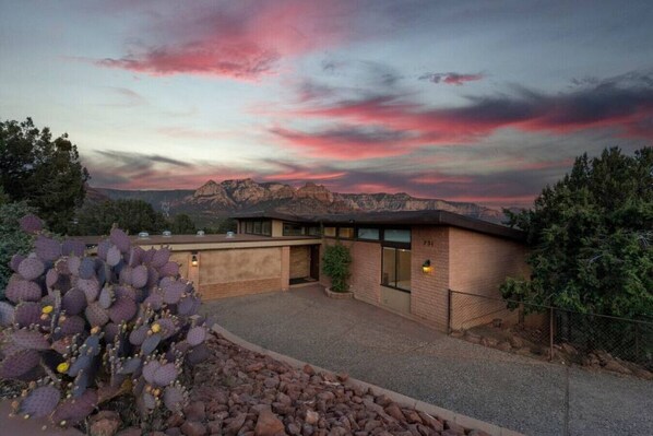 A building with a garage and a small patio area, surrounded by cacti and a mountainous landscape.