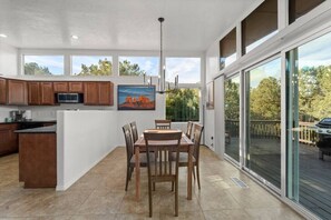 A modern kitchen with wooden cabinets, a central island, and a dining area with a table and chairs.