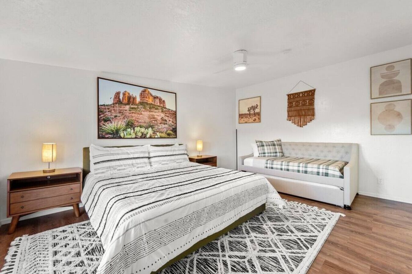 Une chambre à coucher comprenant un lit, un canapé, une œuvre d’art accrochée au mur et un plancher en bois.