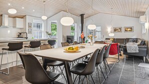 Una cocina moderna con comedor, que incluye una mesa grande, varias sillas e iluminación colgante.