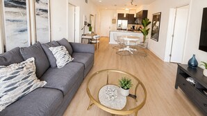 A modern living room with a gray sofa, a round coffee table, and a kitchen in the background. - Marine Life: Smell the Sea, Feel the Breeze (Marina del Rey)