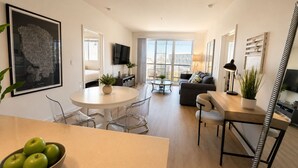 A modern living room with a round dining table, a sofa, and a TV mounted on the wall. - Marine Life: Smell the Sea, Feel the Breeze (Marina del Rey)