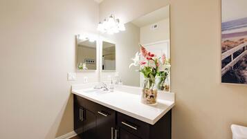 A bathroom with a white sink, black cabinets, a large mirror, and a vase with flowers.
