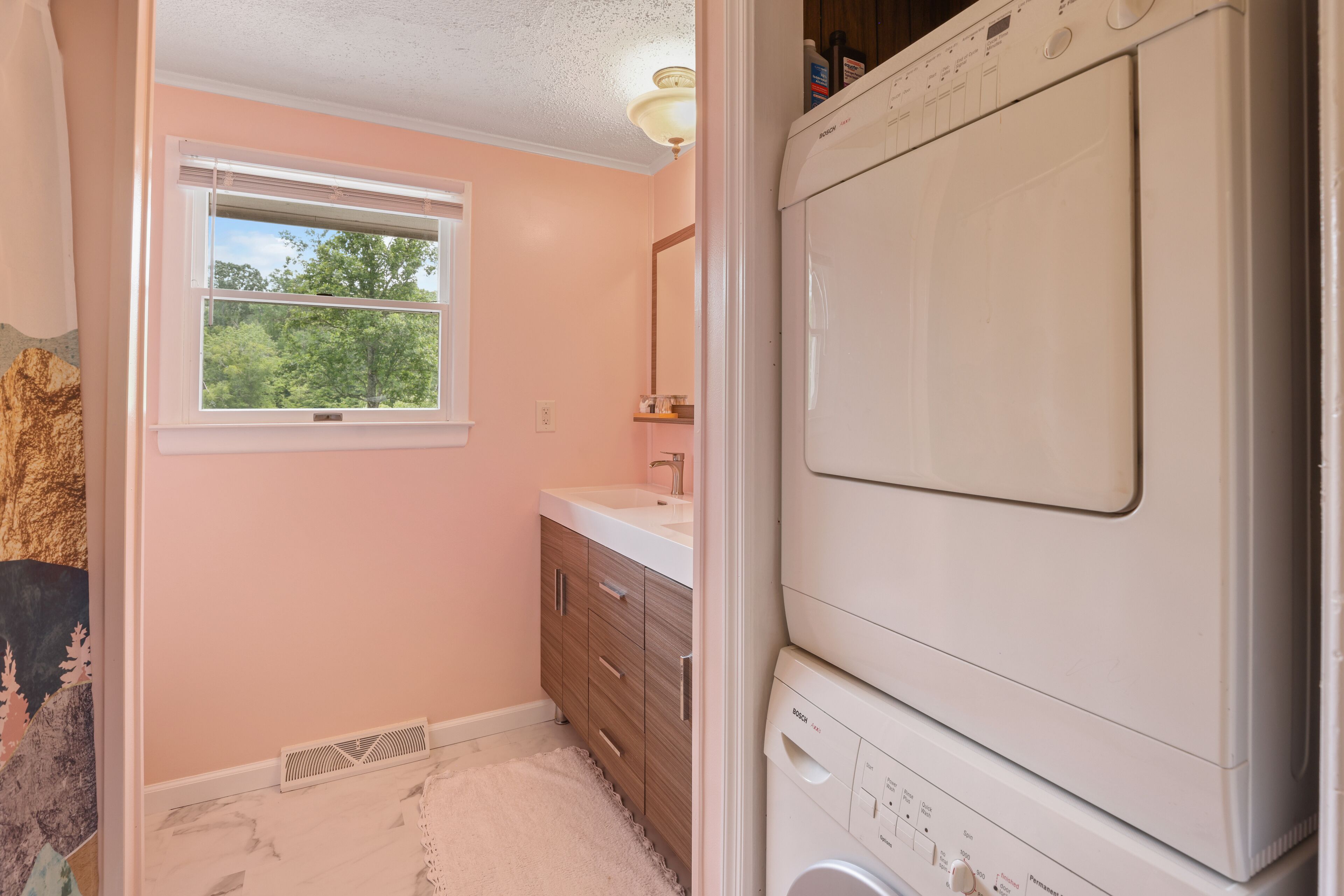 A laundry room with a Bosch washing machine, a window, and a wooden vanity.