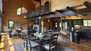 Une cabane en bois spacieuse, dotée d’un coin repas, d’une cheminée et d’un balcon.