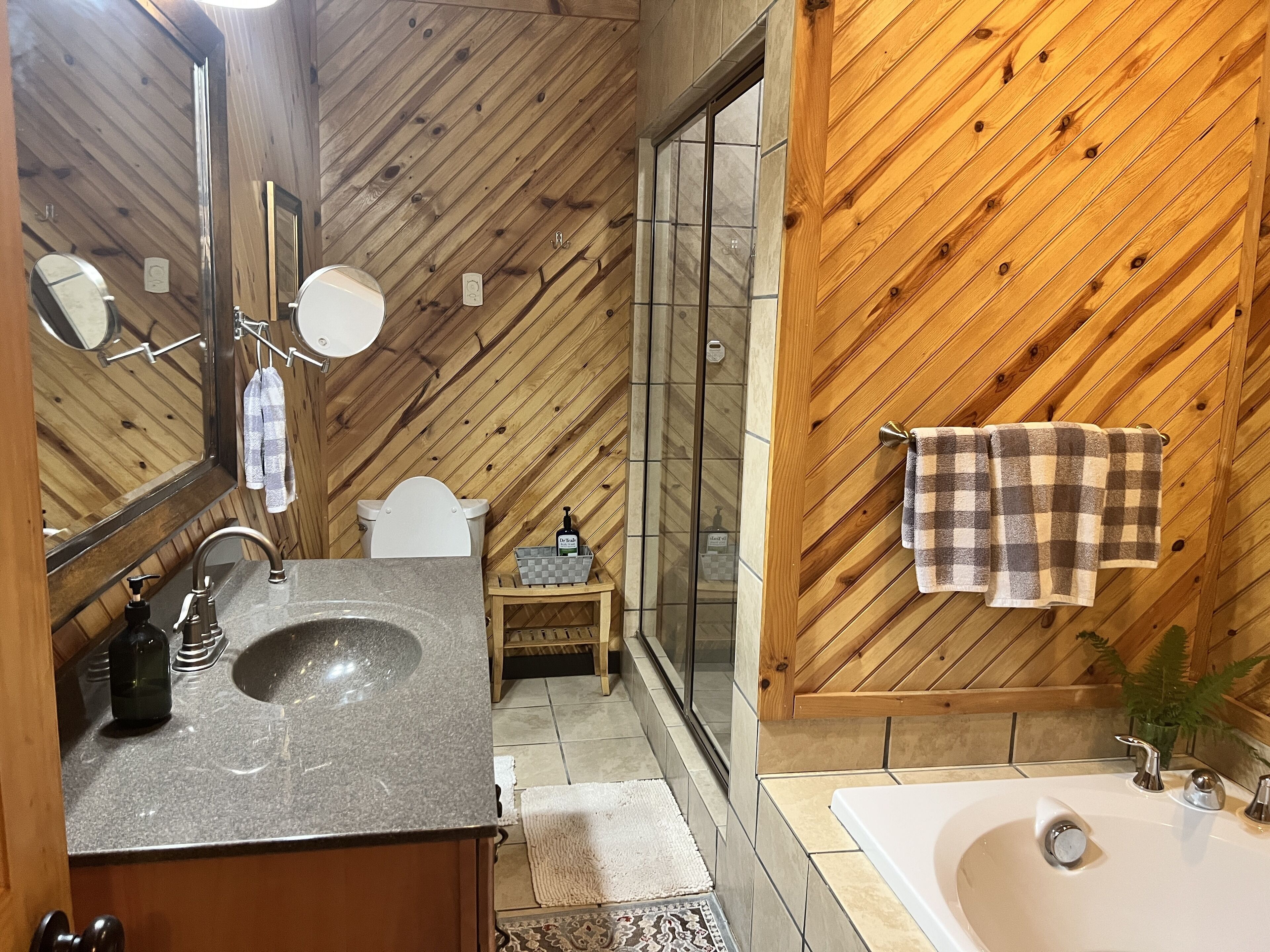 Un baño con pared de madera, un lavabo, un inodoro y una zona de ducha.